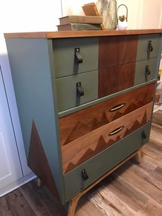 an old dresser has been painted green, brown and blue with geometric designs on the drawers