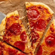 two slices of pepperoni pizza on a piece of parchment paper with a spatula