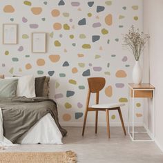 a bed room with a neatly made bed next to a wall covered in polka dots