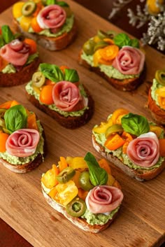 many small sandwiches with different toppings on them sitting on a cutting board next to flowers