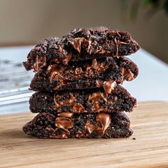 a stack of chocolate cookies on top of a wooden cutting board next to a knife