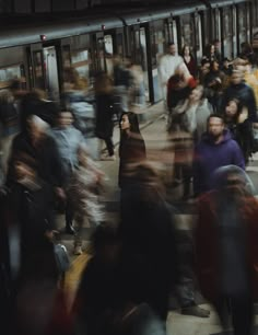 a crowd of people walking down a street next to a train