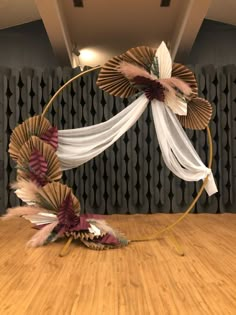 an artistic display with paper flowers and ribbons on the floor in front of a wall