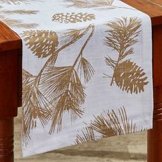 a wooden table topped with a white and brown table cloth covered in pine cones on top of it