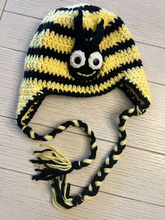 a crocheted hat with eyeballs on it sitting on a white wooden floor