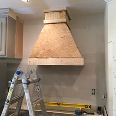 a stove hood being installed on the wall in a kitchen with ladders to it