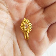 a hand holding a gold ring with a pear shaped stone in it's center