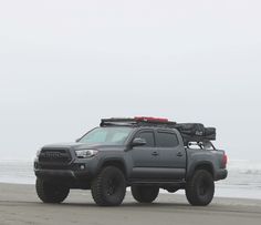 a gray truck parked on top of a sandy beach