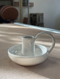 a white vase sitting on top of a table next to a bowl filled with liquid