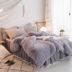 the bed is made up with fluffy purple blankets and pillows on it's sides