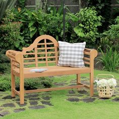 a wooden bench sitting on top of a lush green field next to a garden filled with flowers