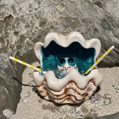 a glass figurine sitting on top of a sandy beach next to a rock