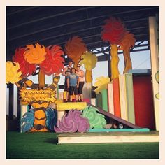 two people standing on top of a stage with fake flowers in front of them,