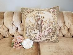 a decorative pillow sitting on top of a couch next to a white rose and a flower