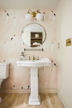 a white pedestal sink sitting under a mirror in a bathroom next to a wall mounted faucet