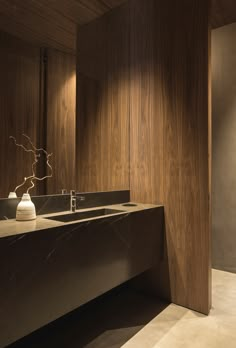 a modern bathroom with wooden walls and counter tops, along with two vases on the sink