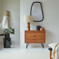 a white room with a wooden dresser and mirror on the wall next to a chair