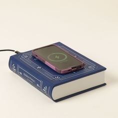 a small electronic device sitting on top of a book with a cord attached to it