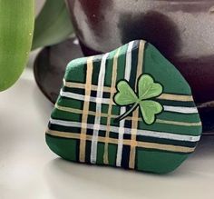 a green rock with a shamrock painted on it sitting next to a potted plant