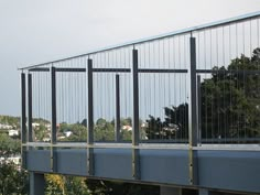 a skateboarder is riding on the edge of a bridge over looking trees and buildings