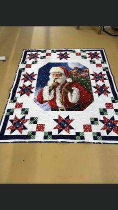 a quilted santa clause is on the floor in front of a christmas tree and stars