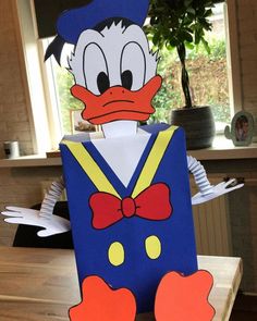 a paper cut out of donald the duck wearing a hat and bow tie, sitting on top of a wooden table