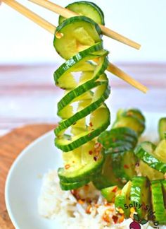 a white plate topped with rice and cucumber on top of chopsticks