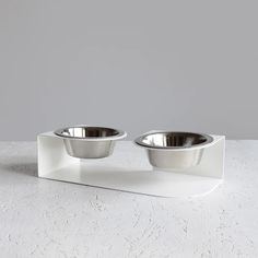 two stainless steel bowls on a white stand