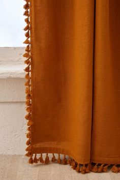 an orange curtain with tassels hanging from it