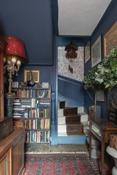 a blue room with bookshelves and pictures on the wall, carpeted stairs