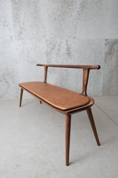 a wooden bench sitting on top of a cement floor next to a concrete wall in an empty room