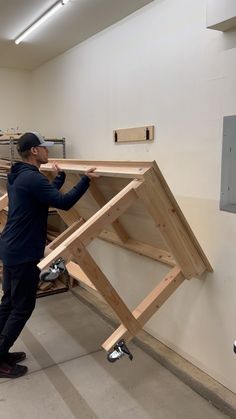 a man standing next to a wooden frame in a room filled with woodworking equipment