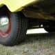 the rear end of a yellow truck with red and white stripes on it's tires