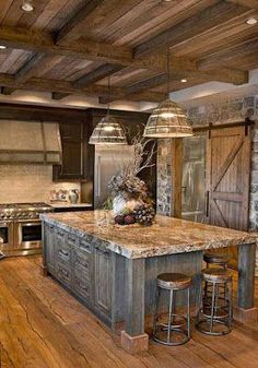 a large kitchen with an island in the center and two pendant lights hanging from the ceiling