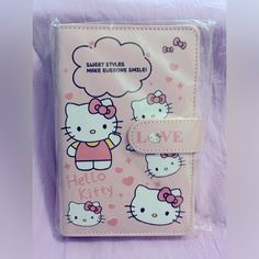 a pink hello kitty passport case sitting on top of a purple sheet