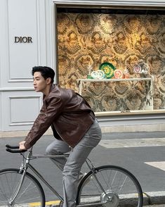 a man riding on the back of a bike down a street next to a store