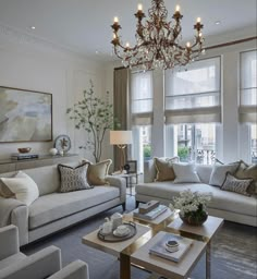 a living room filled with lots of furniture and a chandelier hanging from the ceiling