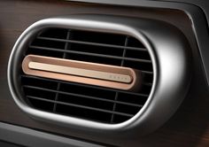 an air vent in the center of a car with wood trims and metal accents