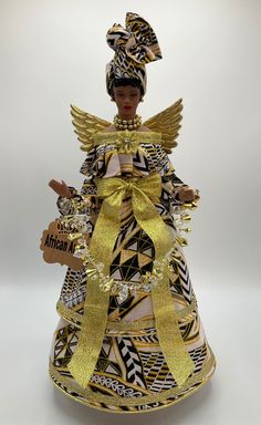 a figurine is dressed in an african print dress and headdress with gold accents