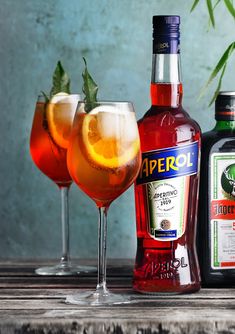 three different types of alcohol sitting next to each other on a wooden table with bottles and glasses