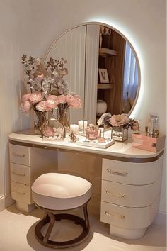 a vanity with flowers and candles on it in front of a round mirror that is lit up