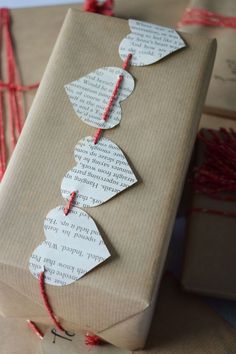 a gift wrapped in brown paper with red string and leaves attached to the wrapping paper