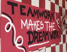 a man is painting a sign on the wall that says teamwork makes the dream work