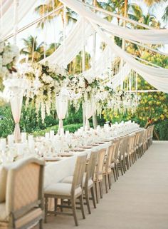 a long table is set up with white flowers and candles for an elegant wedding reception