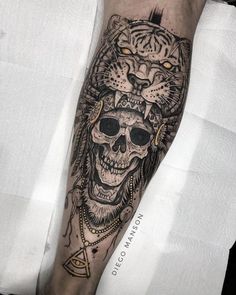 a man's arm with a tiger and skull tattoo on the left side of his leg