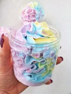 a hand holding a cup filled with colorful frosting