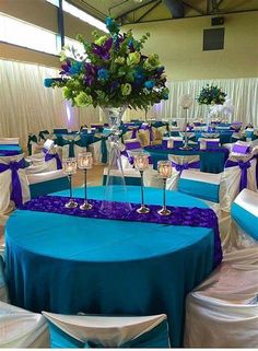 the tables are set up with blue linens and purple sashes for centerpieces