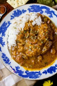 a blue and white plate topped with rice covered in gravy