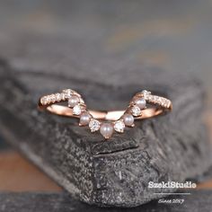 a close up of a ring with pearls on it sitting on top of a rock