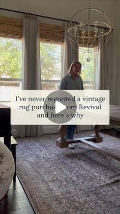 a man standing in front of a living room window next to a rug on top of a wooden floor